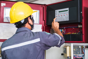 man in hard hat checking fire control panel