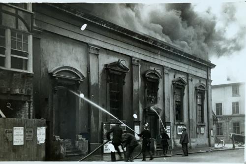 An image of Herne Bay Town Hall on fire in 1925, with a firefighter extinguishing it