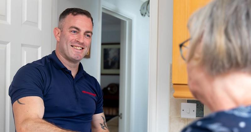A safe and well male colleague talking to a lady in her home