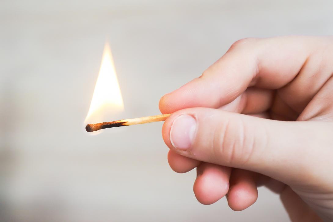 Child's hand holding a lighted match