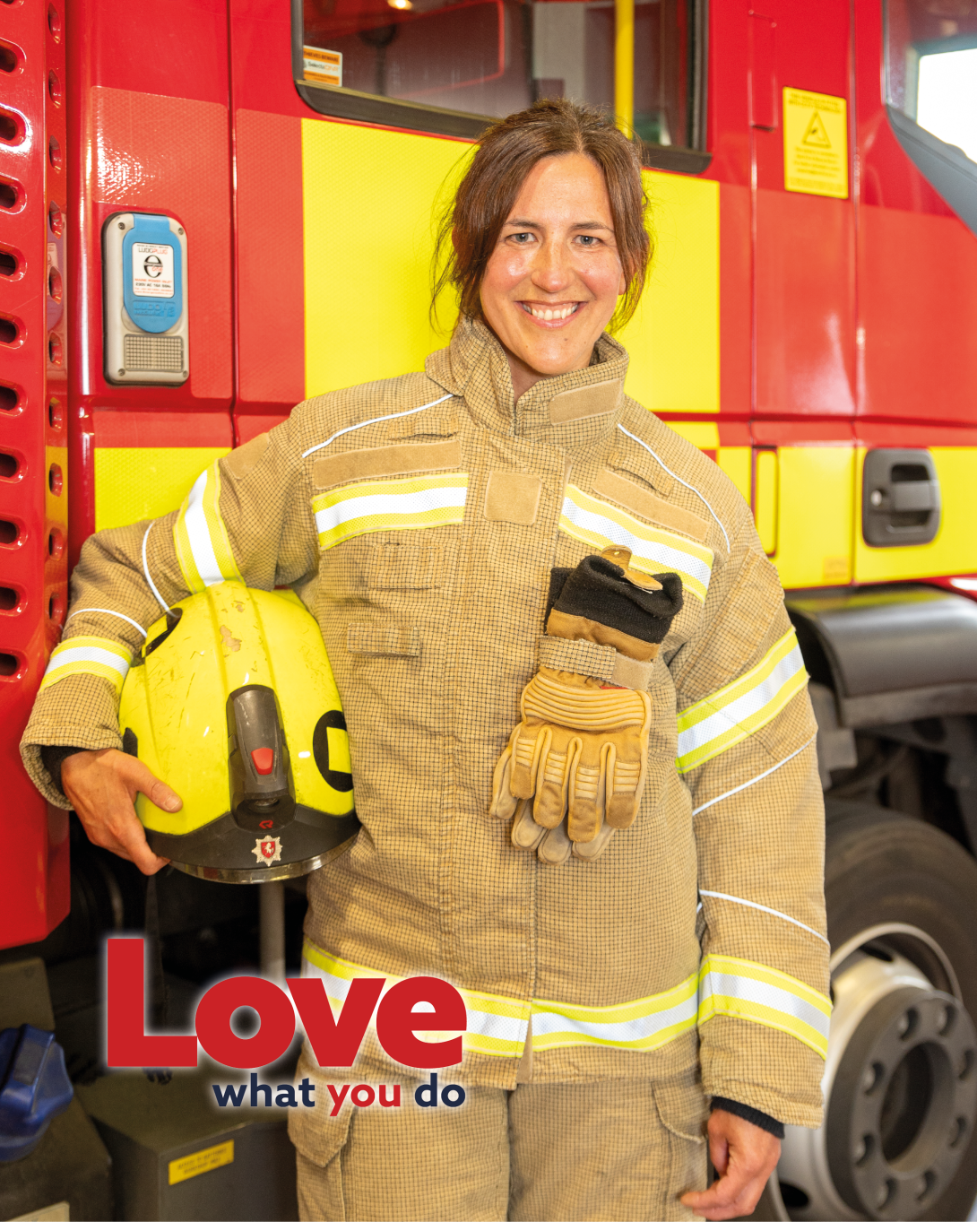 Firefighter in full gear, stood in front of a fire engine