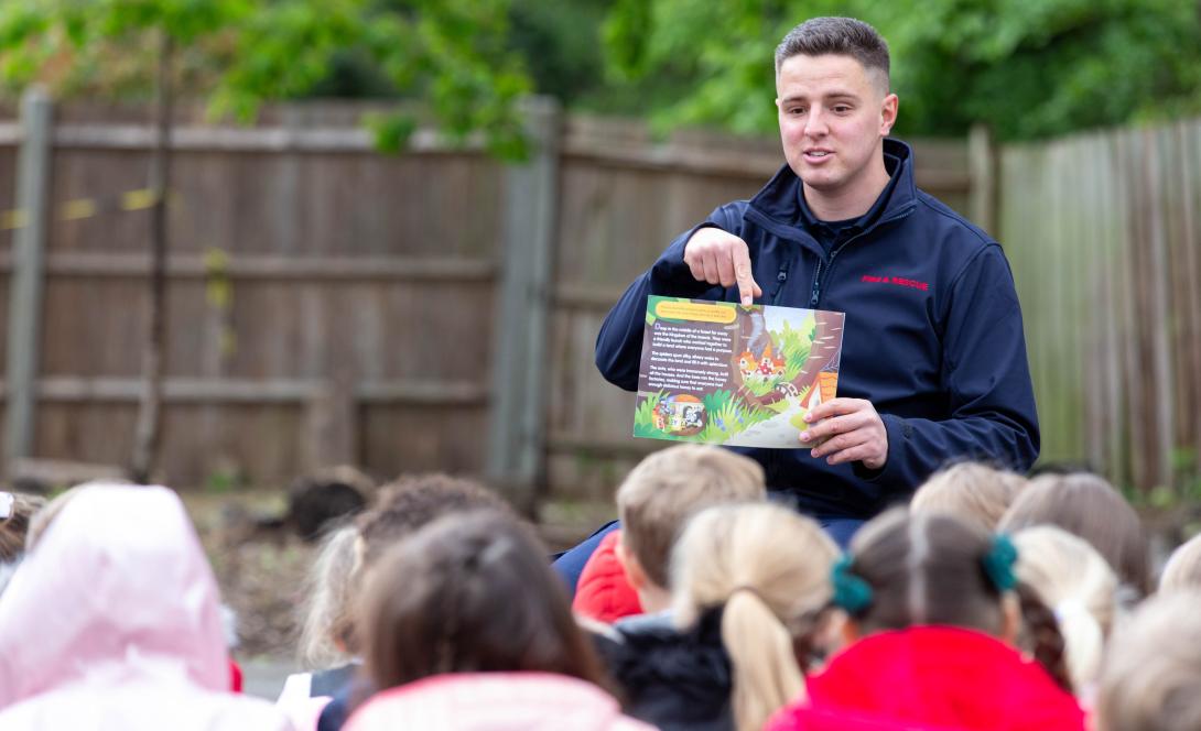 intervention officer reading a book to a group of school children